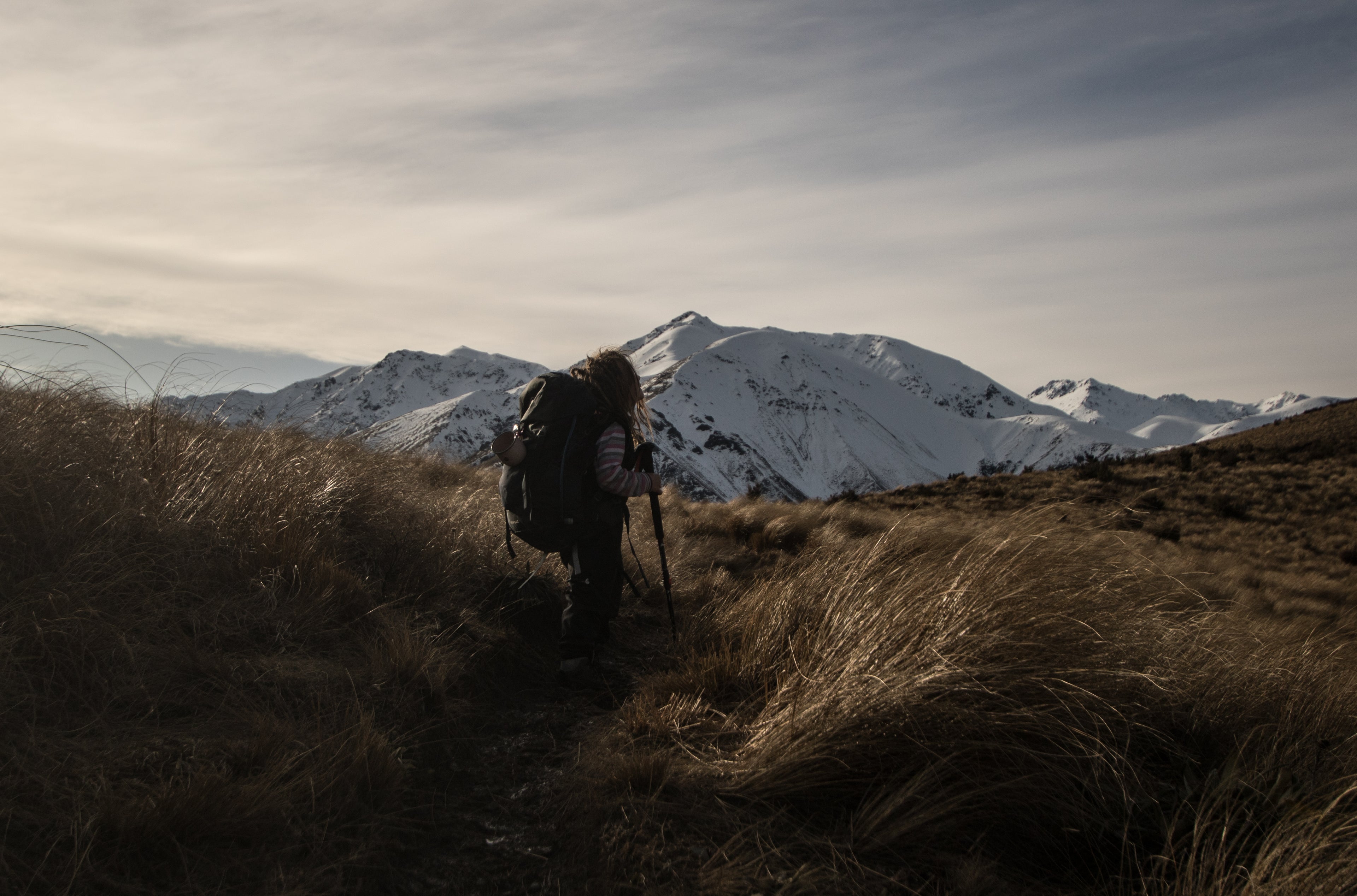 Child with a backpack hiking through a mountainous landscape