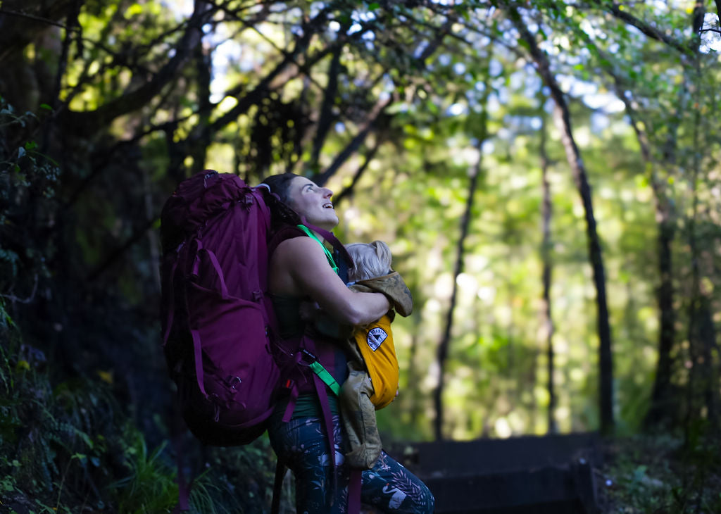 Mum with a large backpack and baby in a forest new zealand