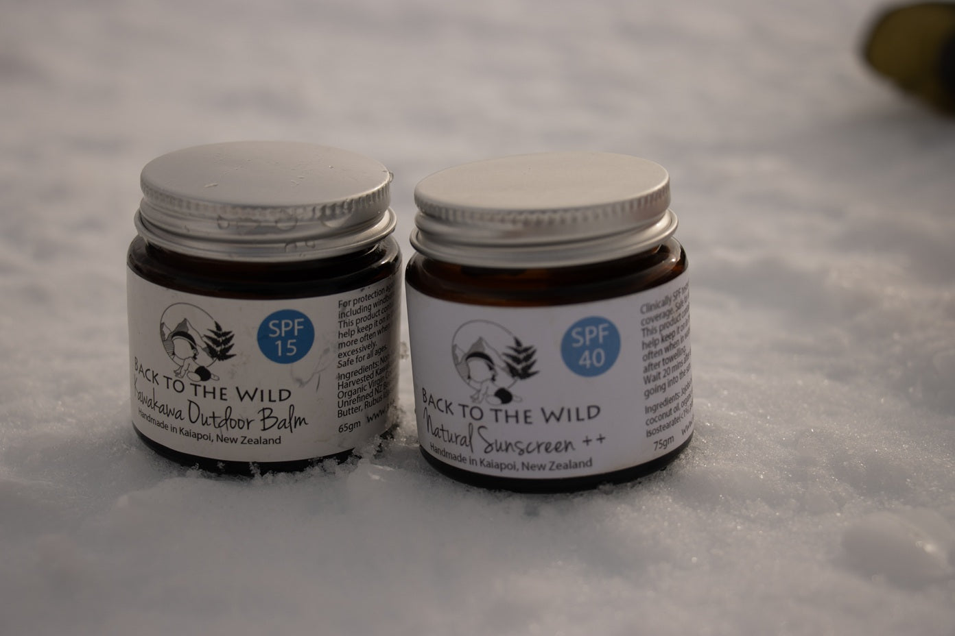 Two jars of 'Back to the Wild' natural sunscreen on a snowy background. Minimal ingredients
