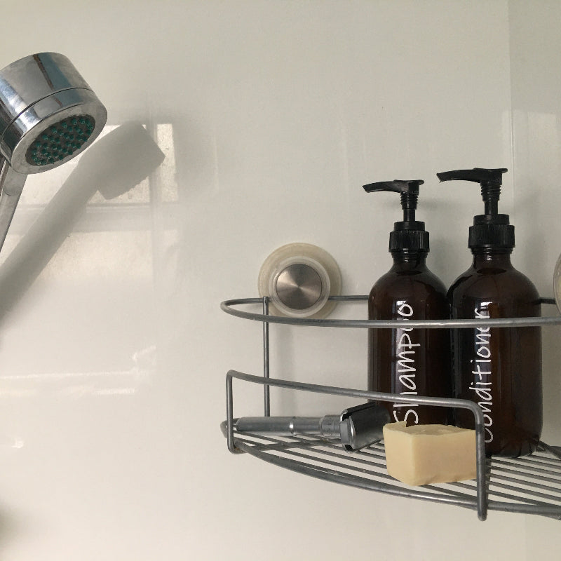 Bathroom shower caddy with shampoo and conditioner bottles, soap, and a shower head.